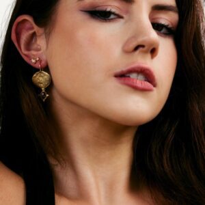 Dark haired model wearing earring stack including gemstone and pearl earrings.