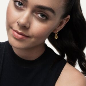 Model wearing interchangeable charm earrings, wearing black top.