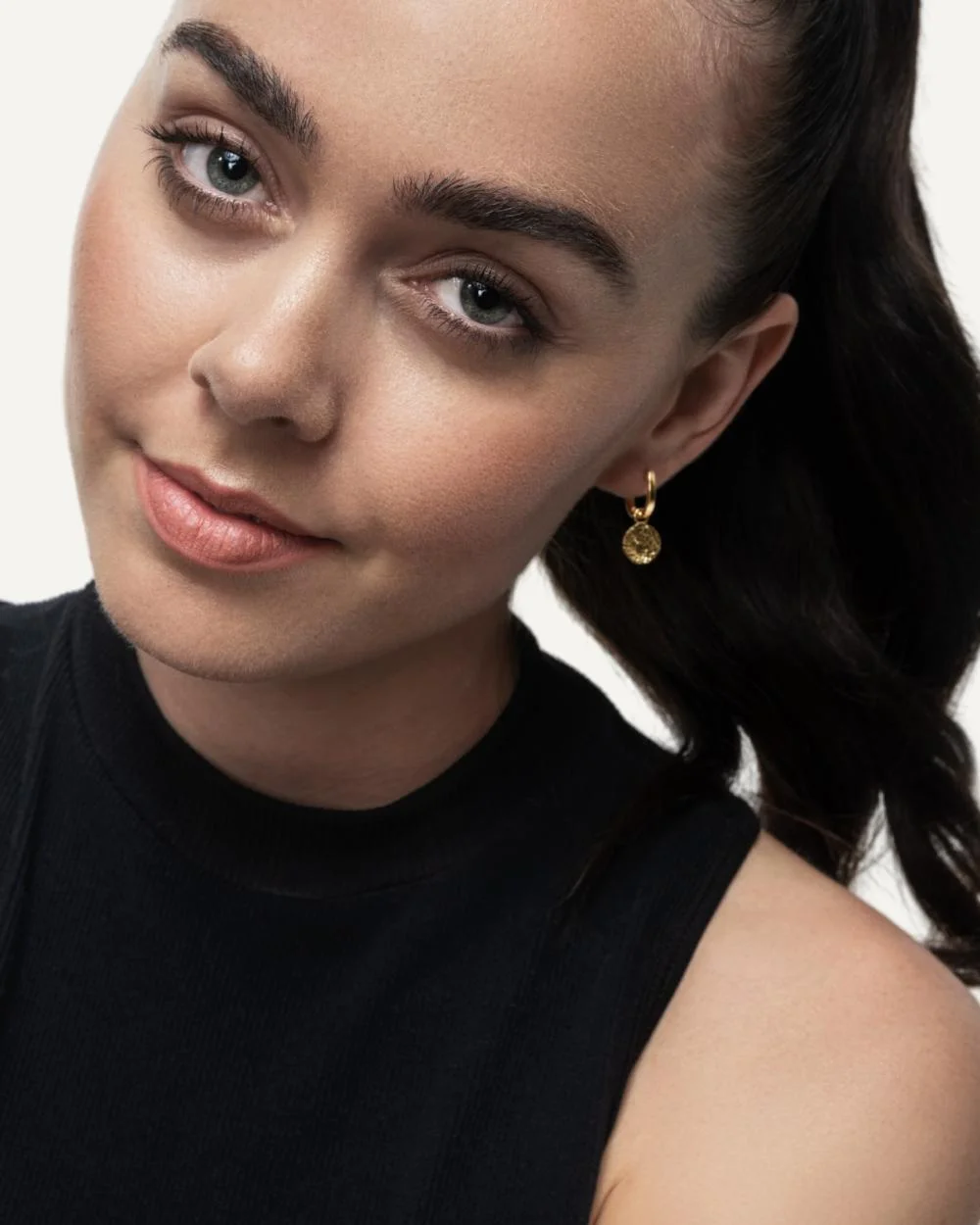 Model wearing interchangeable charm earrings, wearing black top.