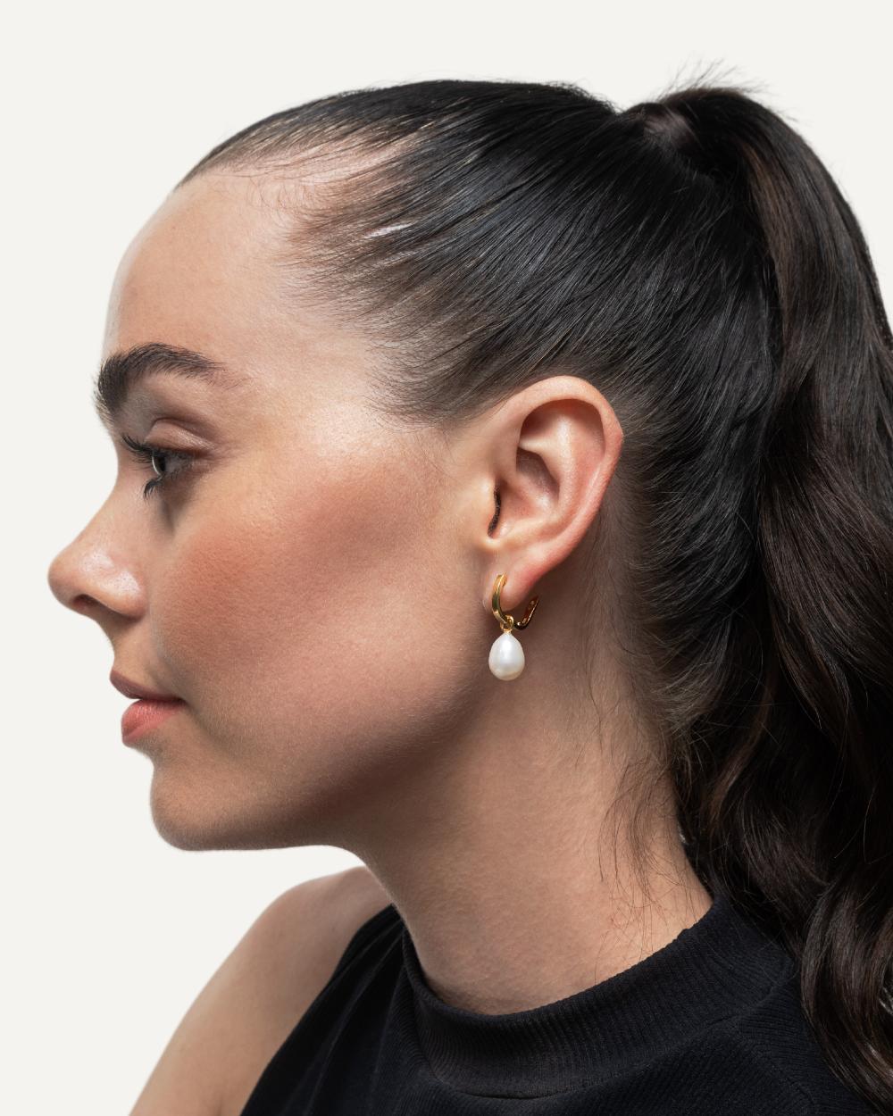 Hoop earrings with pearl charm on dark haired model.