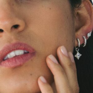 Model wearing diamond simulant hoop earrings in ear stack.