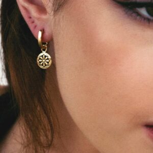 Hoop earring with flower charm close up on model.