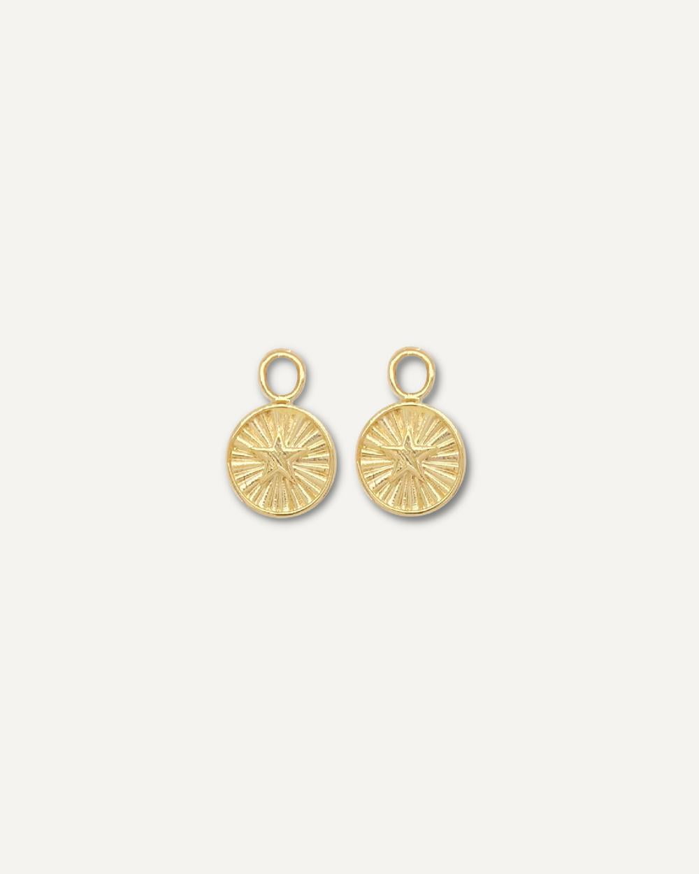 Gold star shaped earring charms on cream background.